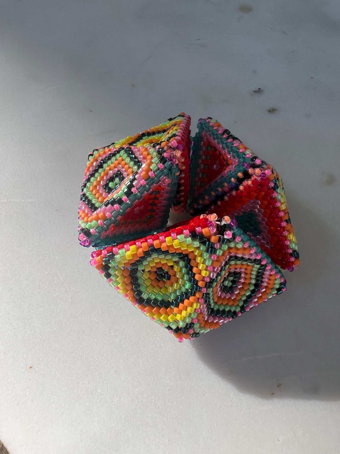 Colorful beaded geometric kaleidocycle on a light gray background