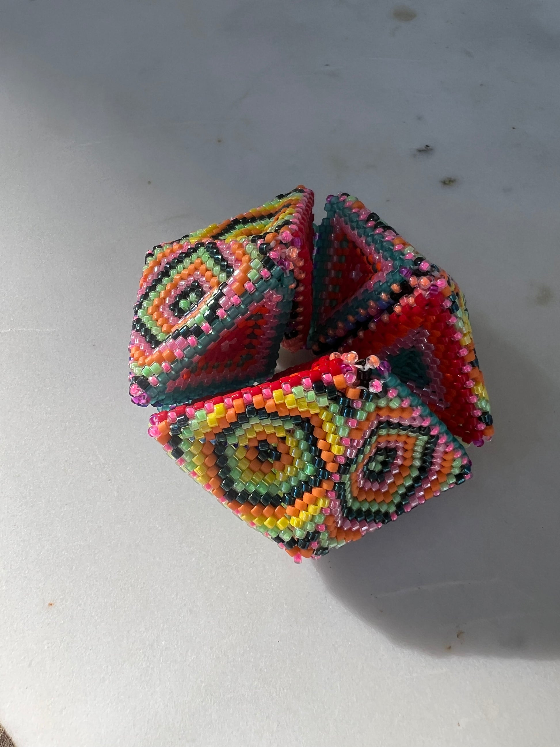 Colorful beaded geometric kaleidocycle on a light gray background