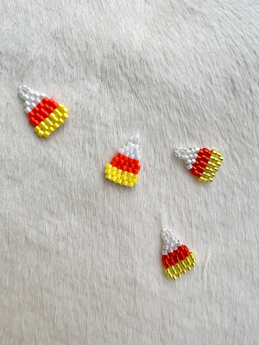 Candy corn-shaped beaded charms on a gray fabric background