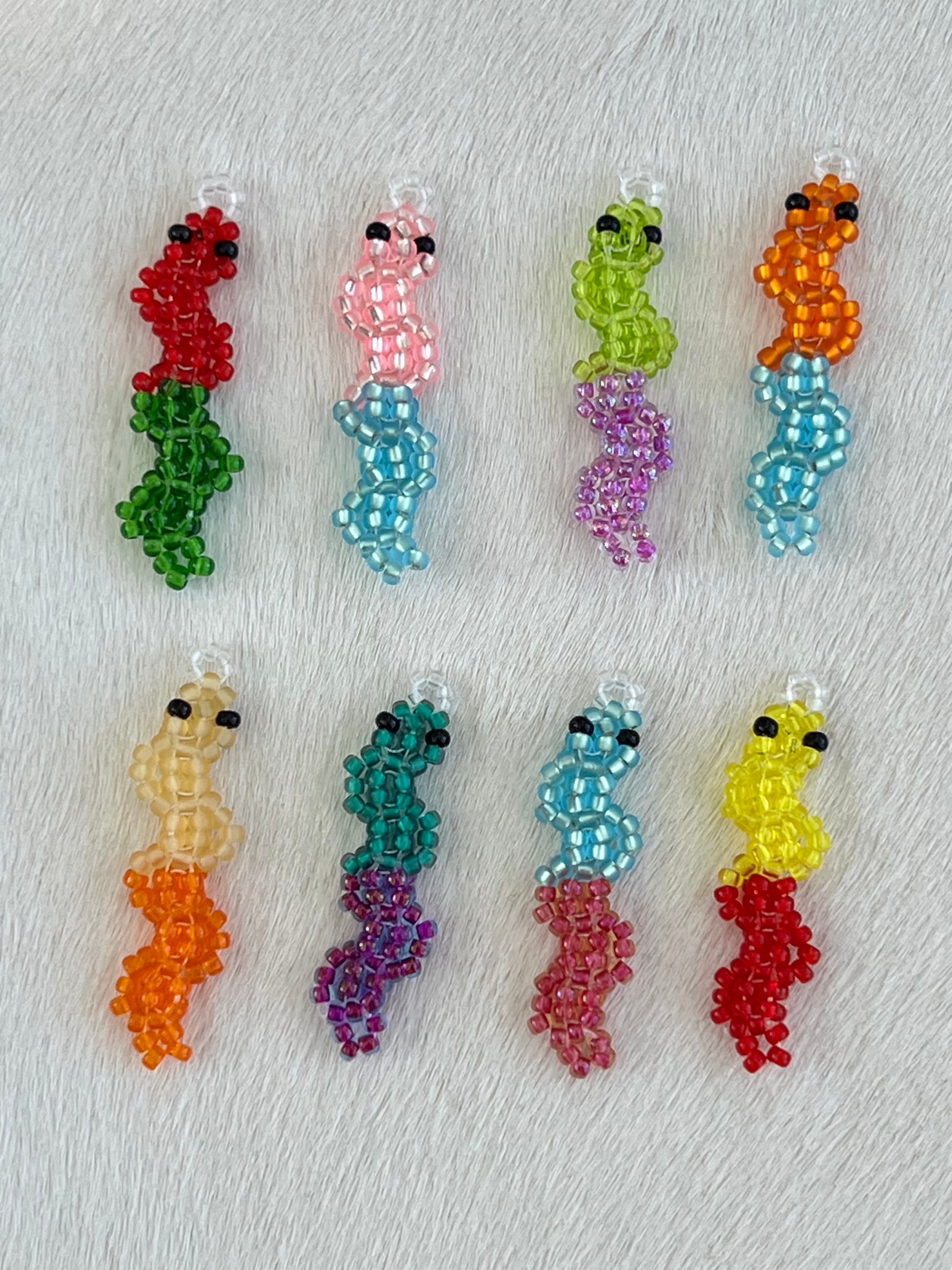 Set of colorful beaded gummy worm charms on a textured surface