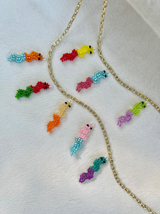 Colorful beaded gummy worm pendants on a gold chain against a white background