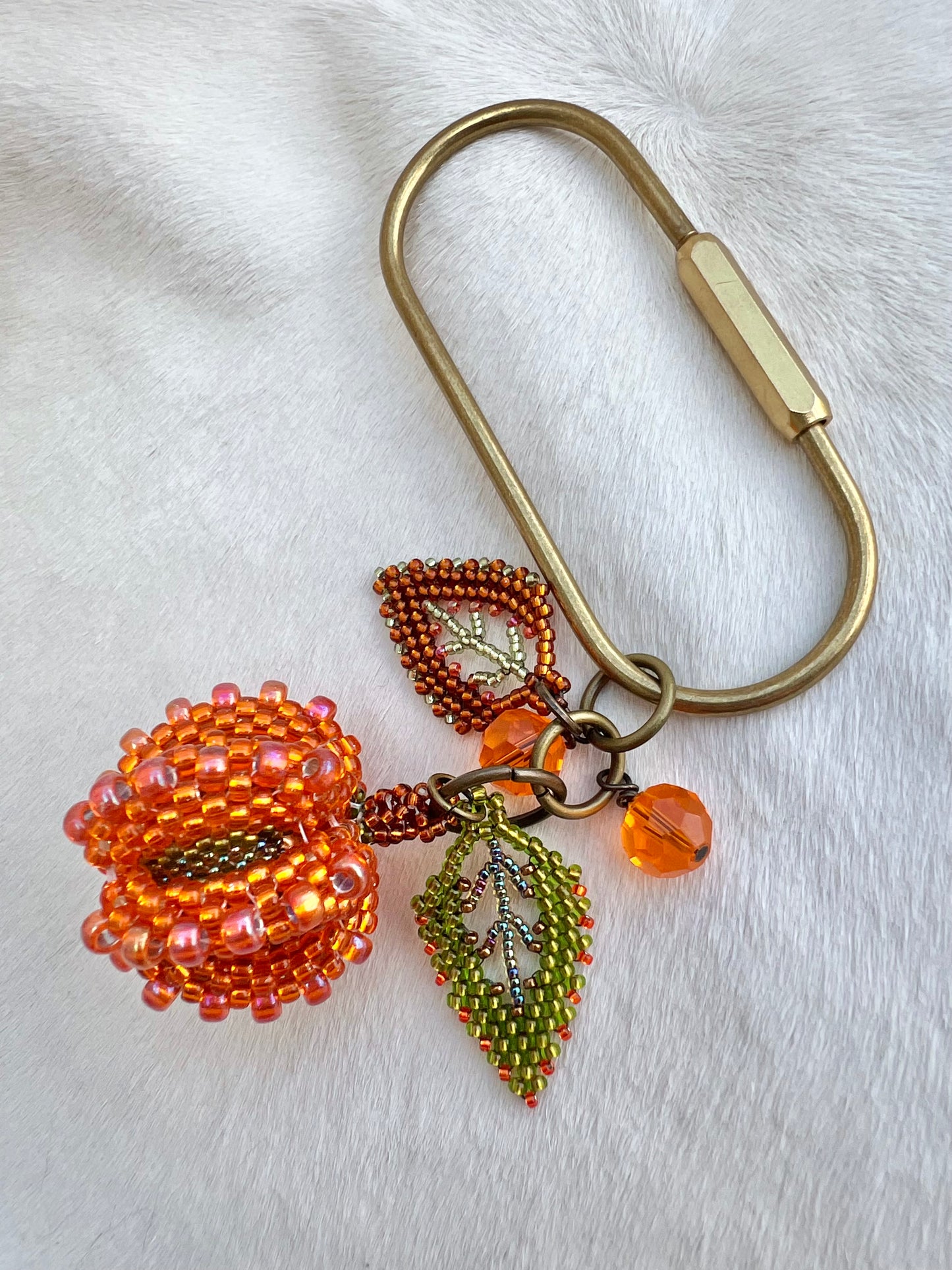 Beaded pumpkin keychain with leaf charms on a white background