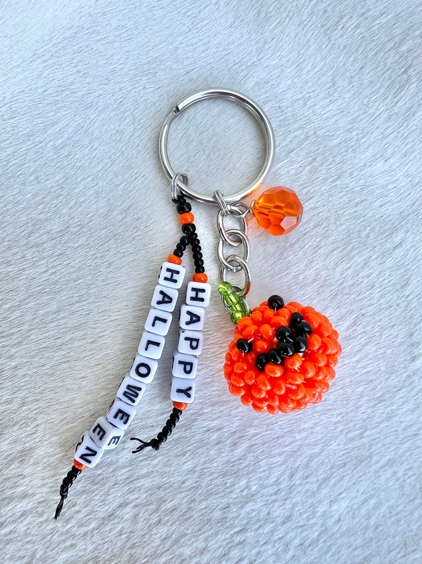 Keychain with pumpkin charm and 'Happy Halloween' beads on a light gray background