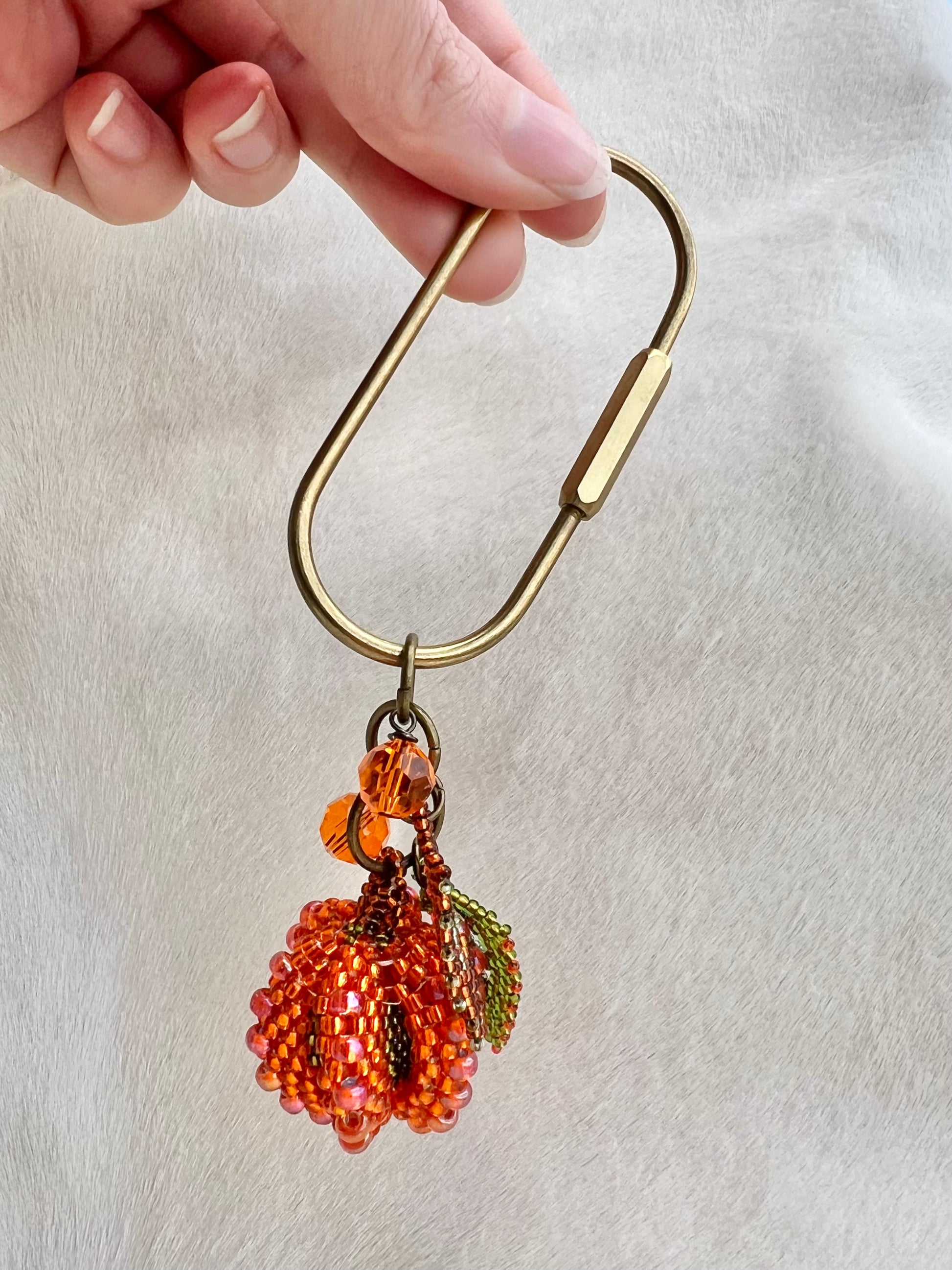 Beaded pumpkin keychain with gold carabiner on a light background
