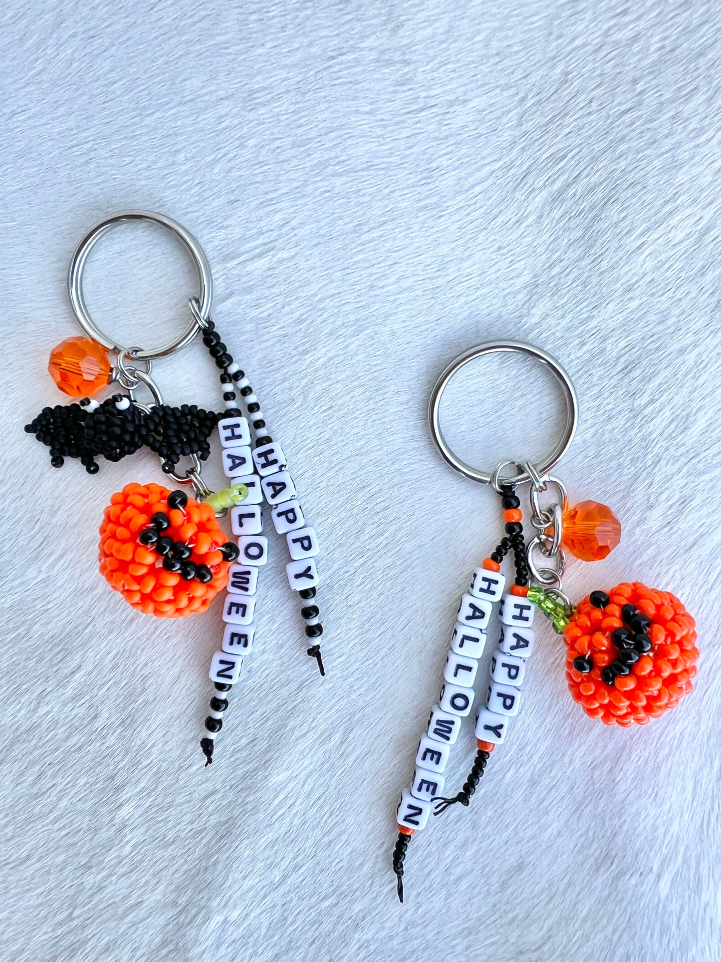 Two Halloween-themed keychains with pumpkins and 'Happy Halloween' beads on a light gray background.