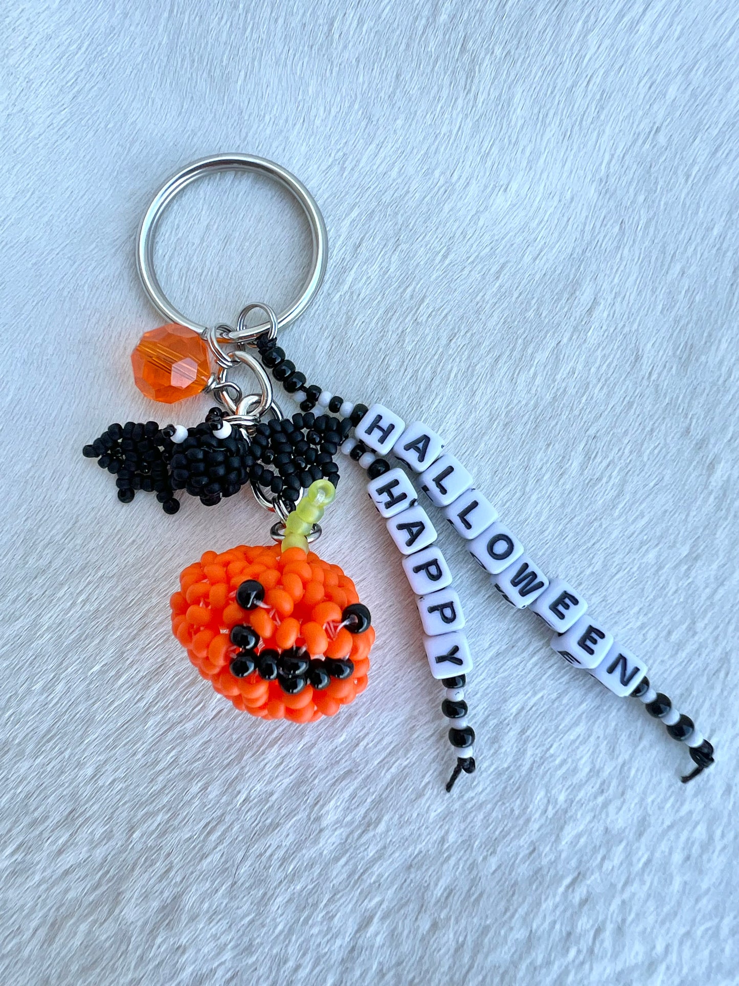 Halloween-themed keychain with pumpkin, bat, and 'Happy Halloween' banner on a light gray background