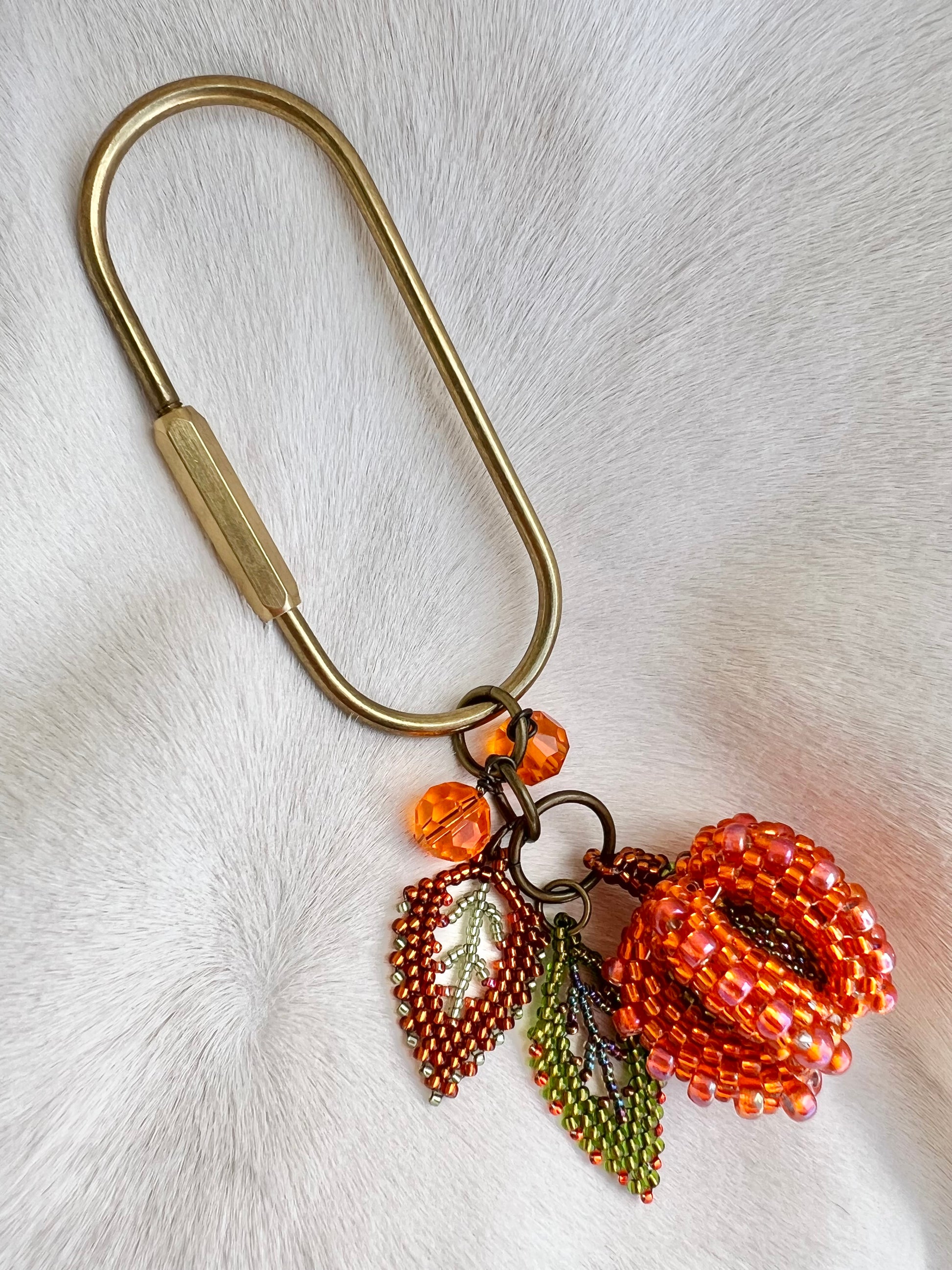 Beaded pumpkin keychain with metal clip on a white fur background