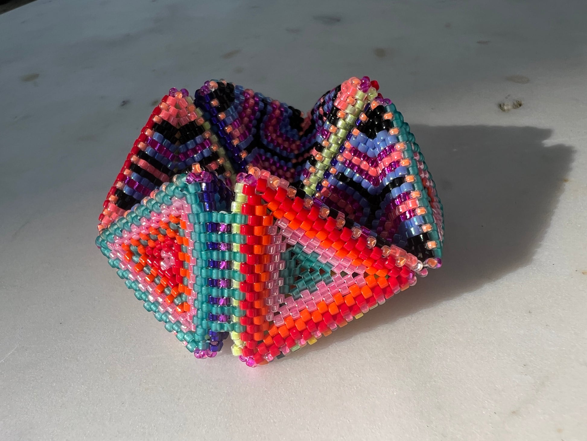 Colorful beaded geometric kaleidocycle on a light background